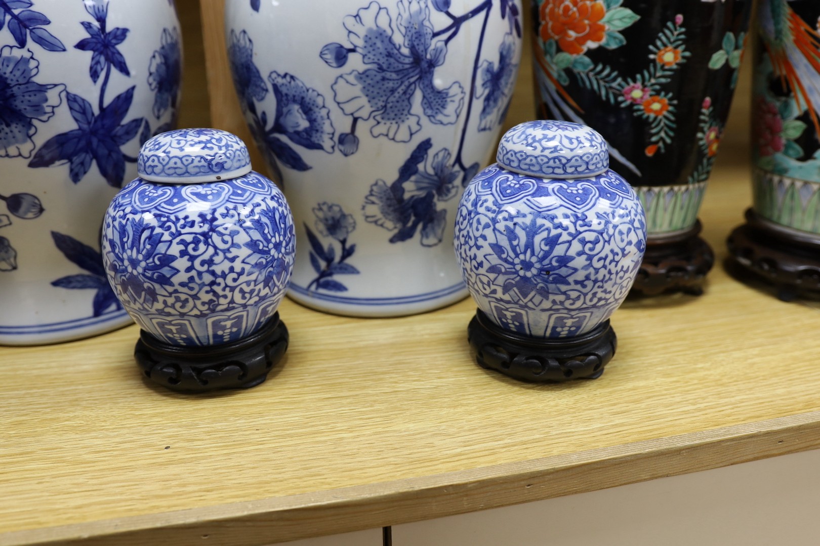 A pair of Japanese black ground vases, a pair of Chinese blue and white vases and covers, a similar pair of jars and a vase, four wood stands. Largest 41cm